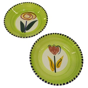 May include: Two ceramic bowls with a light green rim and a white center. Each bowl features a different floral design in the center. The rims are decorated with a dark blue dotted pattern.
