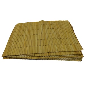 May include: A stack of bamboo placemats. Each mat is made of thin, light brown bamboo strips arranged in a rectangular pattern. The mats are stacked on top of each other, showing the texture and natural color of the bamboo.