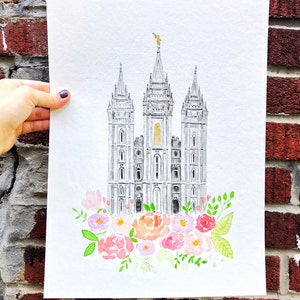 May include: Watercolor painting of a gray building with a gold statue on top. The building is surrounded by pink, white, and green flowers.
