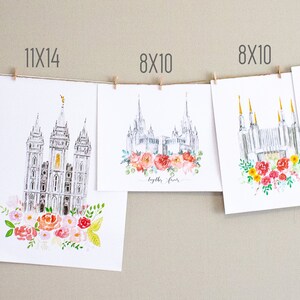May include: A collection of watercolor prints featuring a white temple with colorful floral wreaths. The prints are displayed on a wall with clothespins and string. The prints are available in various sizes, including 5x7, 8x10, and 11x14 inches.