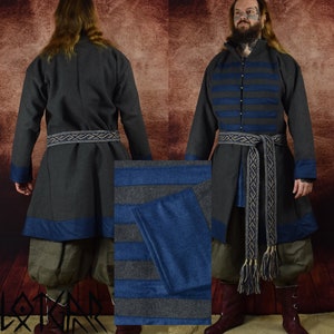 May include: A long-sleeved tunic with a dark grey wool exterior and blue wool trim. The tunic has a high collar and a belt with a woven pattern. The tunic is worn over a pair of dark grey trousers.