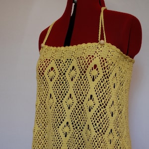 May include: A yellow crochet top with a delicate, lacy pattern. The top has thin straps and a loose, flowing fit.