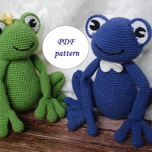 Pode incluir: Dois bichos de pel&uacute;cia de sapo de croch&ecirc;, um verde com uma coroa dourada e um azul com uma gravata borboleta branca, est&atilde;o lado a lado. O texto "PDF pattern" est&aacute; em um c&iacute;rculo branco. Os sapos t&ecirc;m olhos grandes e p&eacute;s palmados.