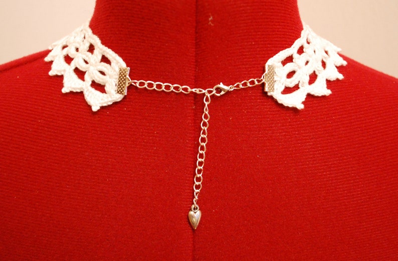 May include: White crocheted choker necklace with a silver chain and heart charm.