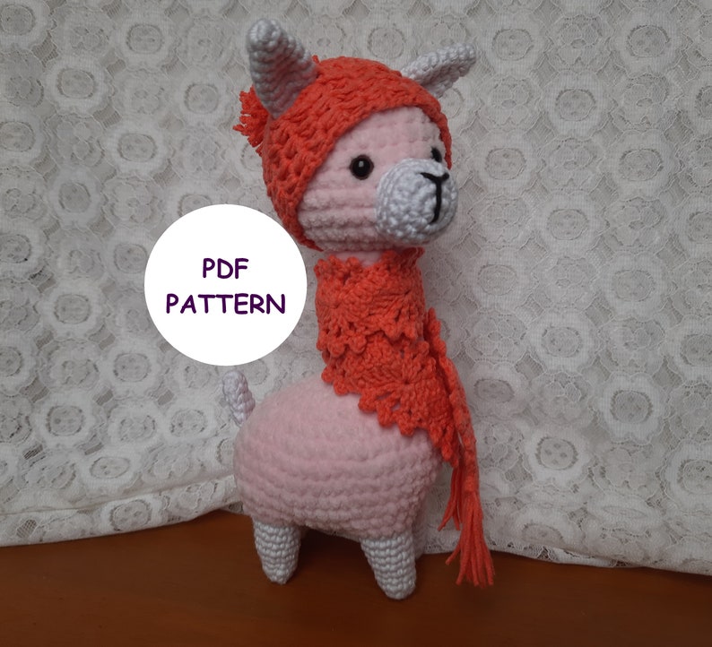 May include: A pink crocheted llama wearing a red crocheted hat and scarf. The text "PDF PATTERN" is visible in the image.