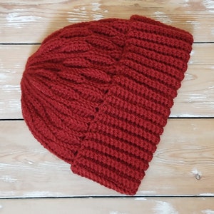 May include: A red knitted beanie hat with a ribbed texture. The hat is folded down at the brim.