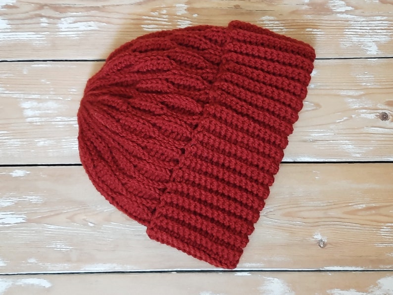 May include: A red knitted beanie hat with a ribbed texture. The hat is folded down at the brim.