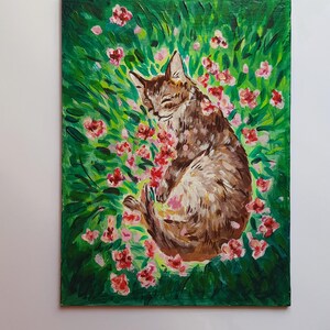 Puede incluir: Una pintura de un gato atigrado marr&oacute;n durmiendo en un campo de hierba verde y flores rosas.
