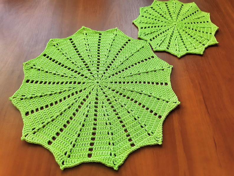 May include: Two green crocheted doilies with a starburst pattern. The larger doily is 12 inches in diameter and the smaller doily is 8 inches in diameter.