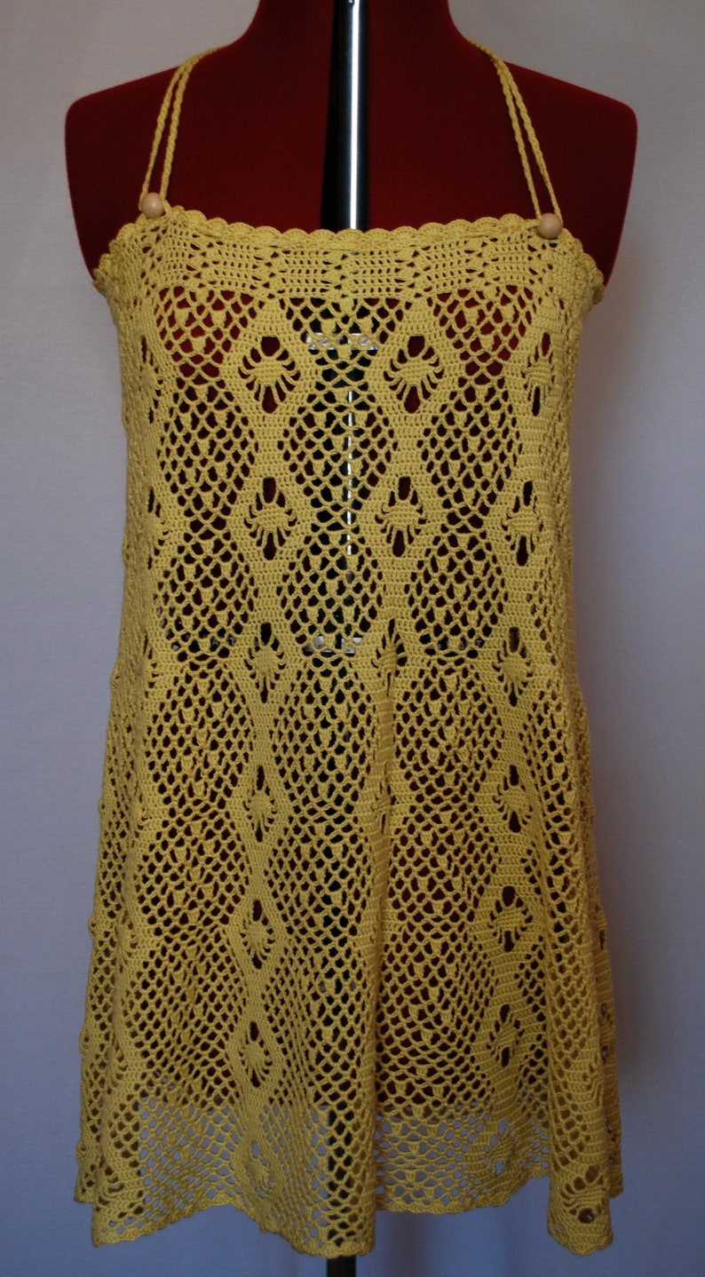 May include: A yellow crochet top with a delicate pattern. The top has a loose fit and a scoop neckline.