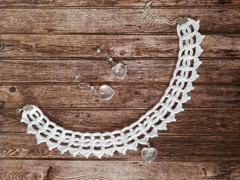May include: White crocheted necklace with a heart-shaped crystal pendant. Matching heart-shaped crystal earrings are also included.