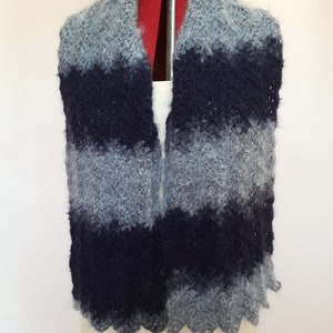 May include: A blue and gray striped knitted scarf with a scalloped edge.
