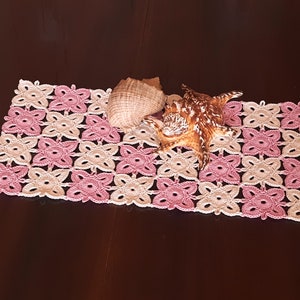 May include: A pink and cream crocheted doily with two seashells on top.