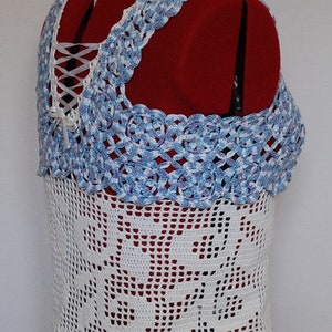 Puede incluir: Top de crochet blanco con un ribete de crochet azul y blanco. El top tiene un detalle de encaje en la espalda.