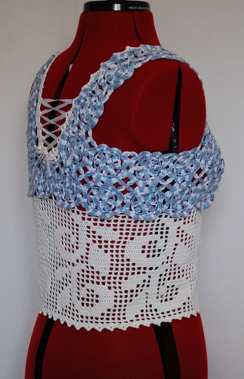 Puede incluir: Top de crochet blanco con un ribete de crochet azul y blanco. El top tiene un detalle de encaje en la espalda.