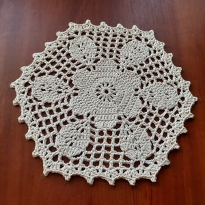 May include: A white crocheted doily with a delicate floral design. The doily is circular and has a scalloped edge.