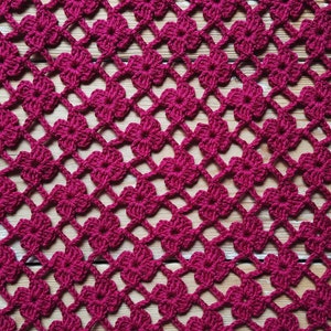 Puede incluir: Primer plano de un encaje de ganchillo con un patr&oacute;n repetitivo de flores burdeos. El encaje est&aacute; hecho con un hilo fino y tiene un aspecto delicado y de encaje.