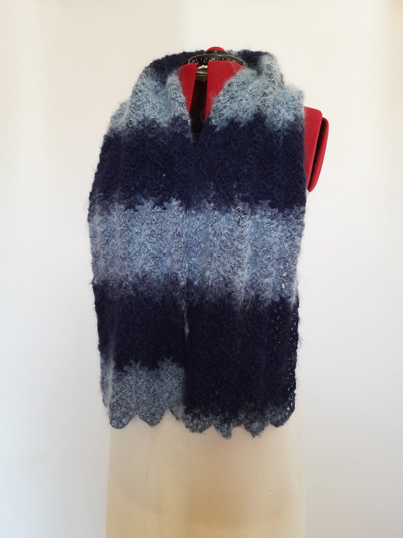 May include: A blue and light blue striped scarf with a fuzzy texture. The scarf is displayed on a mannequin.