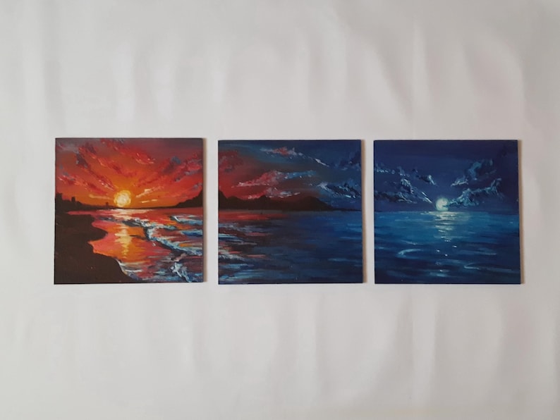 May include: Three paintings depicting a seascape with a sunset, a sunrise, and a moonlit night. The paintings are all in a similar style, with a dark blue background and a light blue foreground. The sunset painting features a bright orange sun setting over the horizon, while the sunrise painting features a bright orange sun rising over the horizon. The moonlit night painting features a bright white moon shining over the horizon.