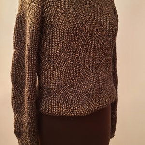 May include: A brown knitted sweater with a textured pattern. The sweater is on a mannequin.
