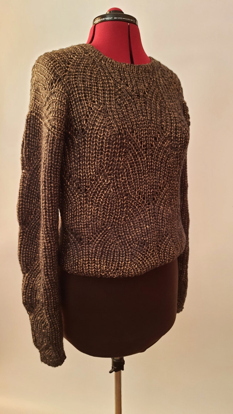 May include: A brown knitted sweater with a textured pattern. The sweater is on a mannequin.