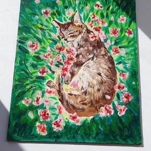 Puede incluir: Una pintura de un gato atigrado marr&oacute;n durmiendo en un campo de hierba verde y flores rosas.