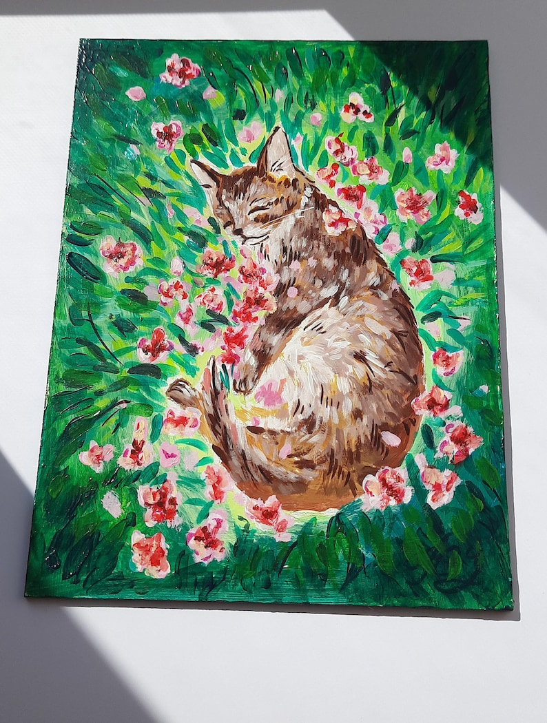 Puede incluir: Una pintura de un gato atigrado marr&oacute;n durmiendo en un campo de hierba verde y flores rosas.