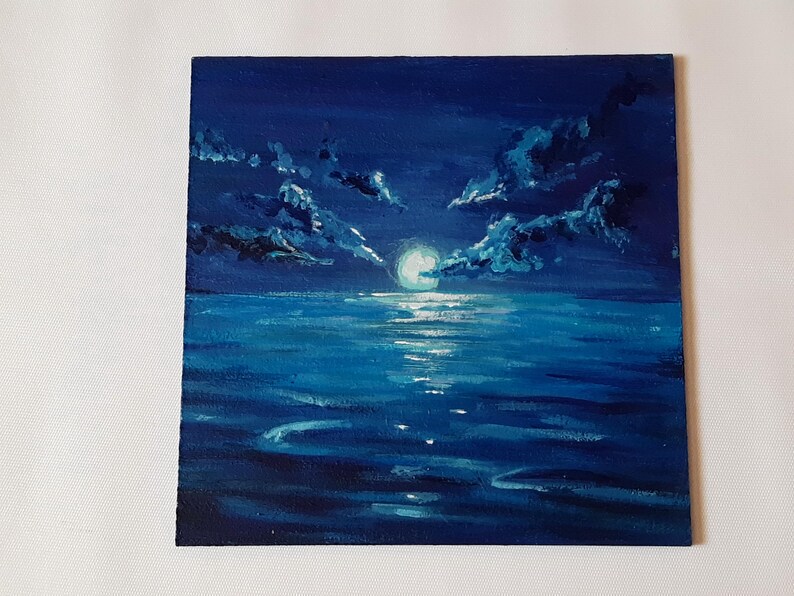 May include: A painting of a moonlit seascape with dark blue clouds and a bright white moon reflecting on the water.