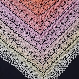 May include: A handmade crochet shawl with a gradient of colors, transitioning from peach to pink and finally to a cream-colored border. The shawl features an open, lacy design with a scalloped edge, perfect for adding a touch of elegance to any outfit.
