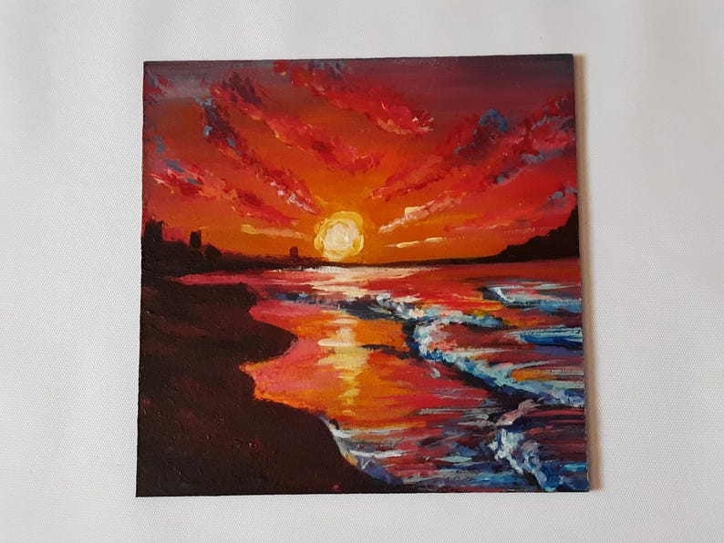 May include: A painting of a sunset over the ocean. The sky is a vibrant orange and red, with clouds painted in shades of pink and purple. The sun is setting in the distance, casting a golden glow on the water. The waves are crashing on the shore, creating a foamy white edge.