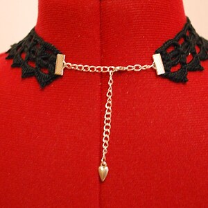 May include: Black lace choker necklace with a silver chain and heart charm. The choker is adjustable with a clasp closure.