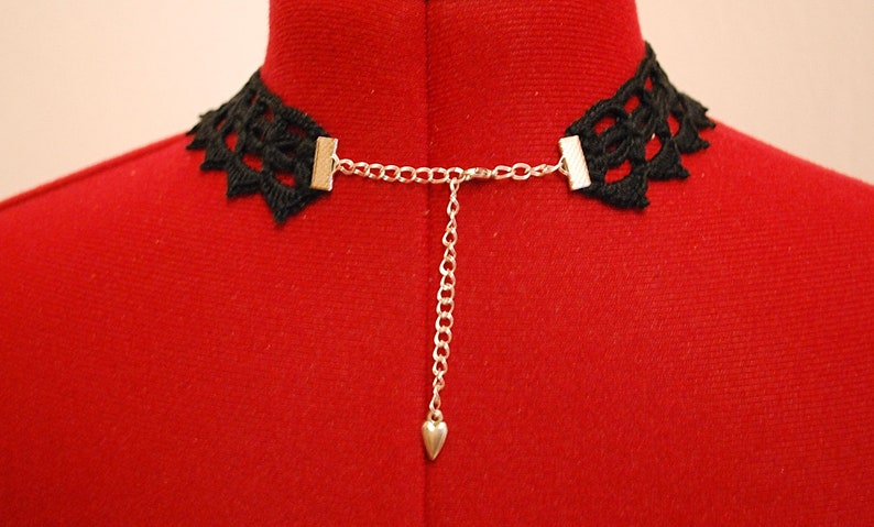 May include: Black lace choker necklace with a silver chain and heart charm. The choker is adjustable with a clasp closure.