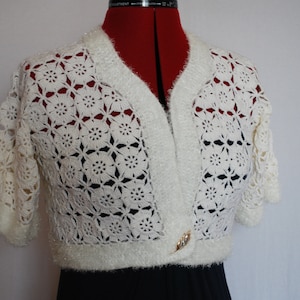 May include: White crocheted shrug with a fuzzy texture and a gold button closure.