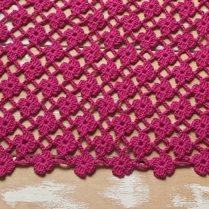 Puede incluir: Primer plano de un encaje de ganchillo rosa con un patr&oacute;n de flores repetido. El encaje est&aacute; hecho con un hilo fino y tiene un aspecto delicado y de encaje.