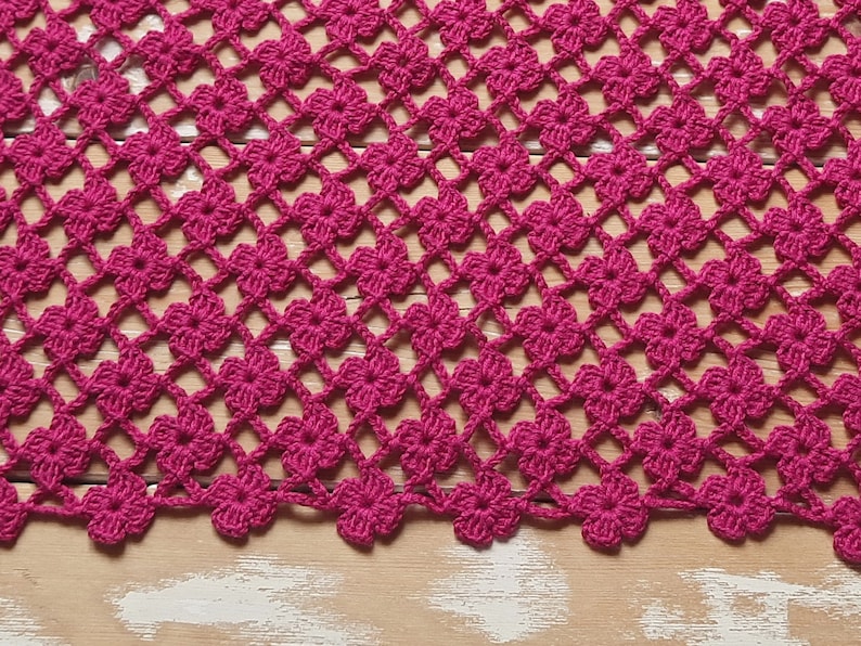 Puede incluir: Primer plano de un encaje de ganchillo rosa con un patr&oacute;n de flores repetido. El encaje est&aacute; hecho con un hilo fino y tiene un aspecto delicado y de encaje.