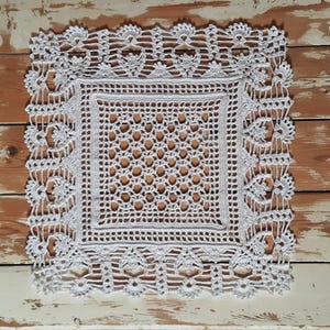 May include: White crocheted doily with a square center and a delicate floral border.