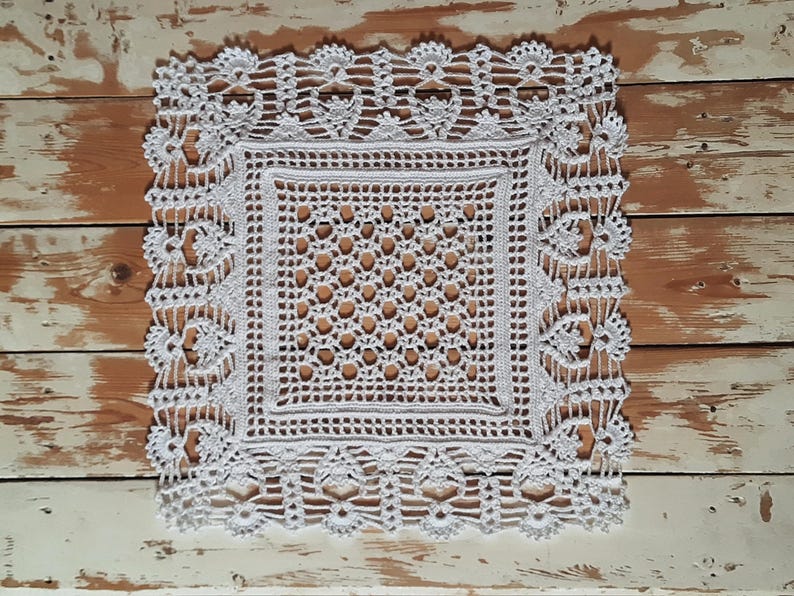 May include: White crocheted doily with a square center and a delicate floral border.