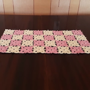 May include: A crocheted table runner with a pink and cream butterfly design.
