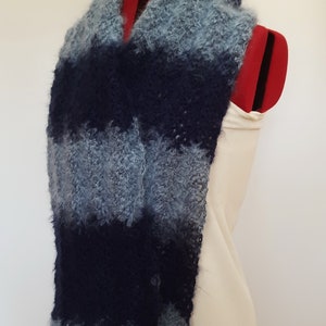 May include: A blue and gray striped scarf made of fuzzy yarn. The scarf is draped over a white dress form.
