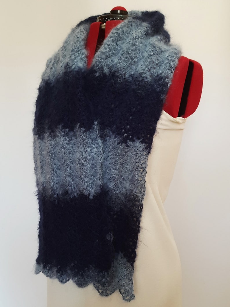 May include: A blue and gray striped scarf made of fuzzy yarn. The scarf is draped over a white dress form.