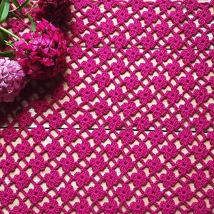 Puede incluir: Primer plano de un encaje de ganchillo rosa con un patr&oacute;n floral. El encaje est&aacute; hecho con un hilo fino y tiene un aspecto delicado y femenino.