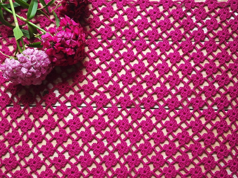 Puede incluir: Primer plano de un encaje de ganchillo rosa con un patr&oacute;n floral. El encaje est&aacute; hecho con un hilo fino y tiene un aspecto delicado y femenino.