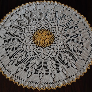 May include: A white crocheted doily with a yellow crocheted center. The doily has a scalloped edge.