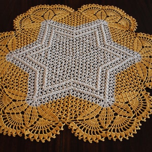 May include: A crocheted doily with a white star in the centre and a yellow border.