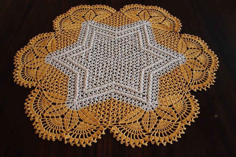 May include: A crocheted doily with a white star in the centre and a yellow border.