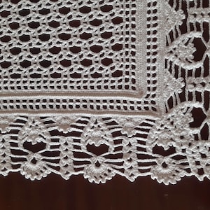 K&ouml;nnte beinhalten: Wei&szlig;e H&auml;keltischdecke mit quadratischem Mittelteil und einem gewellten Rand. Die Tischdecke hat ein zartes Blumenmuster.