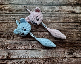 May include: Two crocheted animal toys with tails, one blue and one pink, with the names "Liam" and "Emma" on the tails.