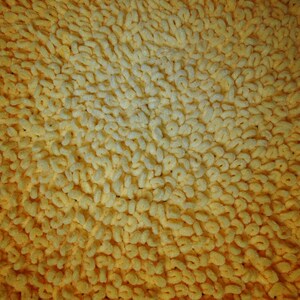 May include: Close-up of a yellow bath mat with a textured surface. The mat is made of soft, looped fibers that create a plush and absorbent surface.