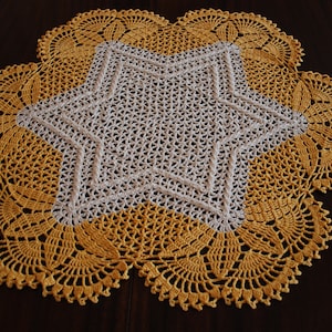 May include: A crocheted doily with a white star in the centre and a yellow border.