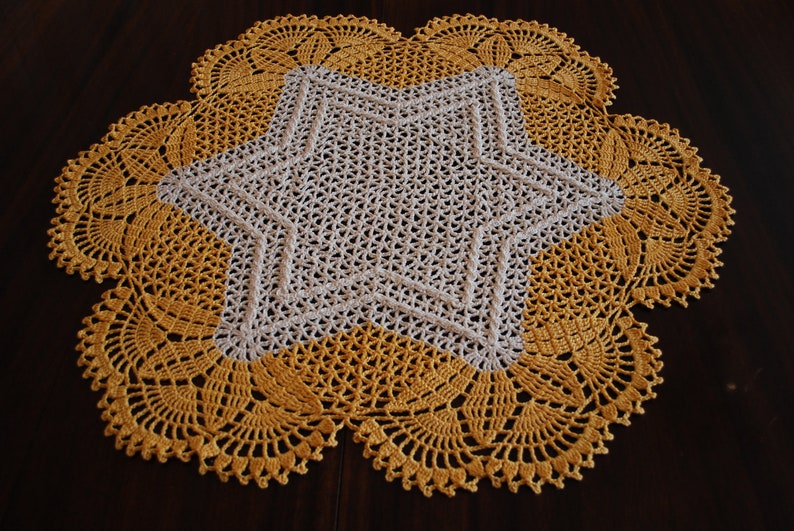 May include: A crocheted doily with a white star in the centre and a yellow border.